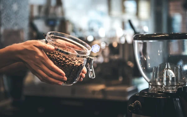 Close up images of Coffee shop owner Show quality coffee beans that are roasted and cooked, in a glass jar, to people and drink concept.
