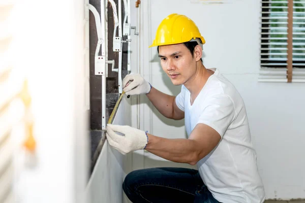 Asian man worker Measuring the windowsill For home improvement work, to people and renovate new home concept.