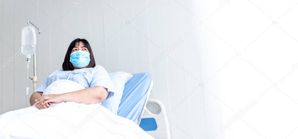 Asian fat woman patients wear a surgical mask Prevent the spread of germs, lying in patient's bed with alone, whit white background, to people health care and Covid-19 infection concept.