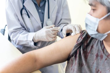 Doktor, cerrahi maske takan Asyalı yaşlılar için aşı ya da Coronavirüs 'ü aşıya ve sağlık hizmetleri konseptine bağlıyor..