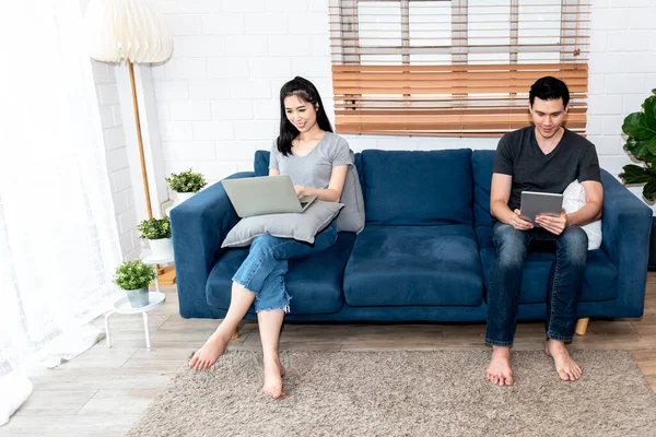 Blurred soft images of Asian couple, husband and attractive wife are resting by using application on notebook computer and tablets at home, to Asian family and technology communication concept.