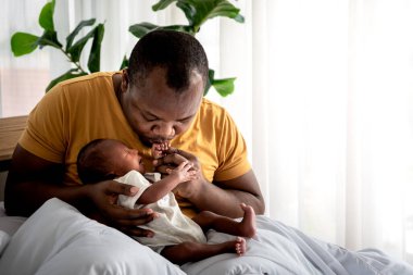 Afro-Amerikalı bir baba öpüşüyor, 12 günlük bebeği siyah tenli yeni doğmuş oğlu mutlu bir şekilde Afrika kökenli Amerikalı bir aileye ve yeni doğan bir bebeğe uzanıyor.