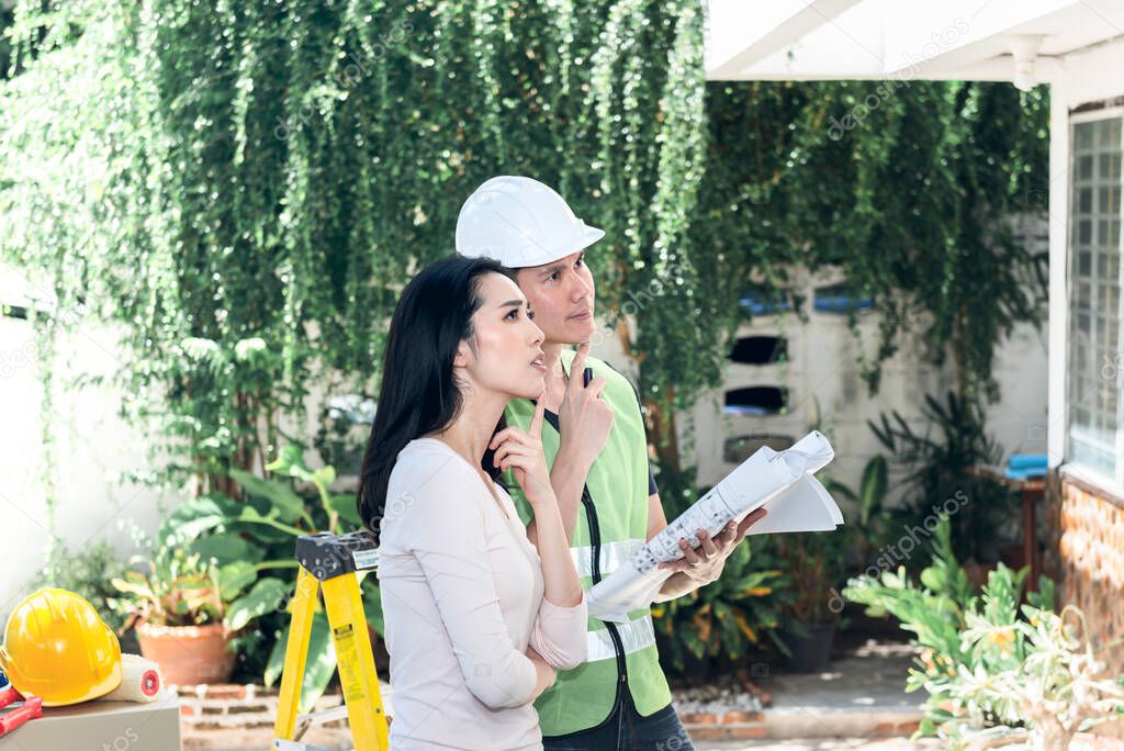 Asian attractive woman And male engineer, are looking at point and discuss about renovating the old house to be new home, to Real estate and renovation concept.