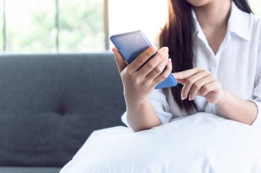 Kanepede oturan bir kadının cep telefonuyla insanlara ve iş dünyasına uygulamasını kullandığı bulanık görüntüler..