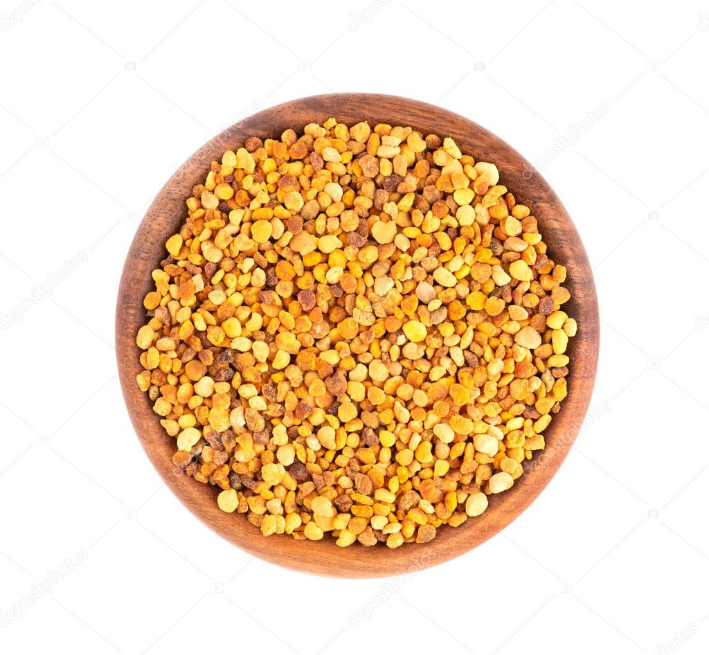 Flower pollen grains in wooden bowl, isolated on white background. Pile of bee pollen or perga. Top view