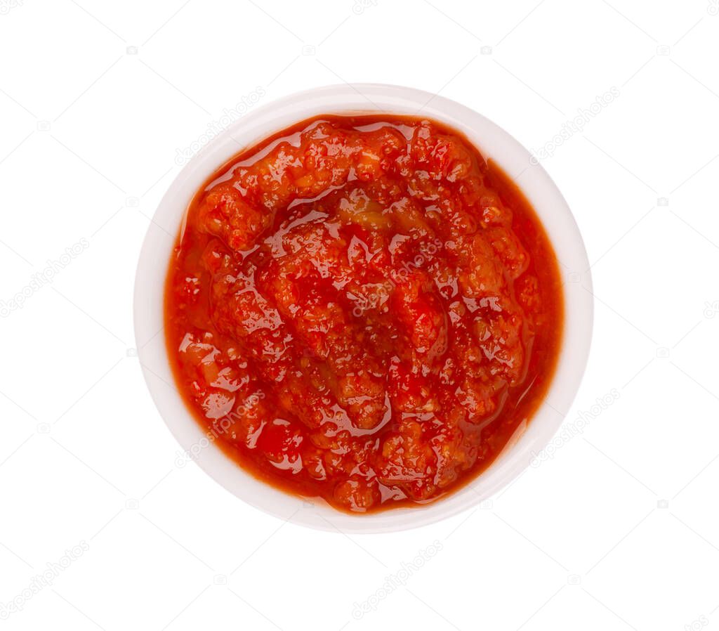 Adjika sauce in bowl, isolated on white background. Spicy tomato and chili pepper sauce. Top view