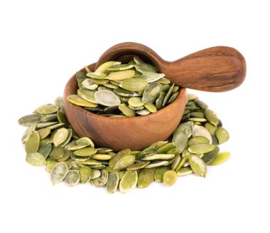 Tahta kasede ve kaşıkta kabak tohumları, beyaz arka planda izole. Yeşil pepita tohumları.