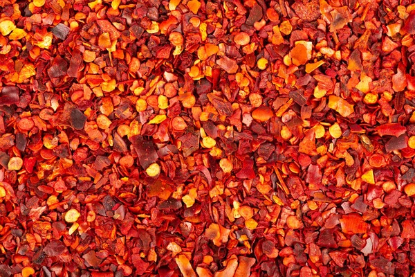 Torkade röda chiliflingor med frön bakgrund. hackad chilicayennepeppar. Kryddor och örter. — Stockfoto