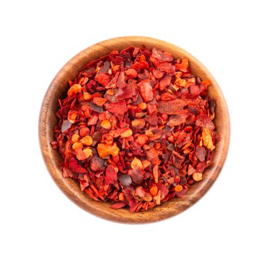 Beyaz arka planda izole edilmiş ahşap kasede kurutulmuş kırmızı biber taneleri. Kırmızı biberli doğranmış kırmızı biber. Baharatlar ve bitkiler. Üst görünüm.