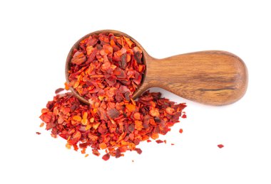 Beyaz arka planda izole edilmiş ahşap kaşıkta kurutulmuş kırmızı biber taneleri. Kırmızı biberli doğranmış kırmızı biber. Baharatlar ve bitkiler.