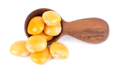 Beyaz arka planda izole edilmiş, ahşap kaşıkta turşulu sarı lupin fasulyesi. Tournus, korunmuş lupinus..