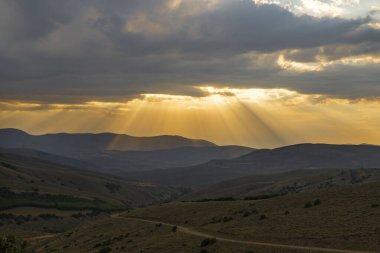 Güneş batarken güneş ışığı bulutların arasından süzülür.