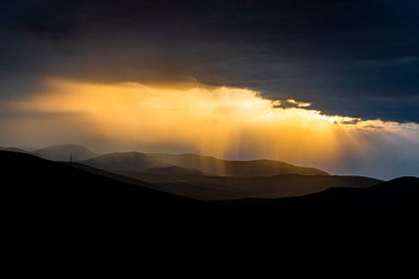 Güneş batarken güneş ışığı bulutların arasından süzülür.