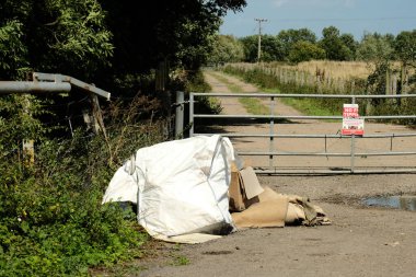 Fly tipped bags on a country lane clipart