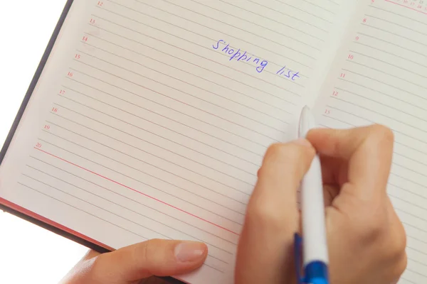 Image of female hand with pen holding shopping list