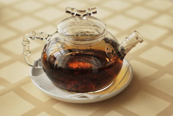 Transparante theepot met zwarte thee op een plaat — Stockfoto
