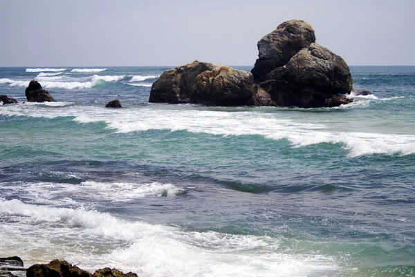 mavi su ve karanlık taşlar ile güzel bir plaj