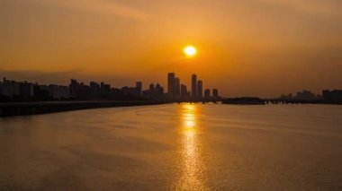 Günbatımı manzaralı modern uzun binalara bakan Han Nehri ve ada nodeulu bir turist teknesi var Güney Kore 'de gün batımında atmosfere bakın.