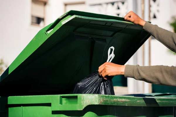 Homem jogando fora saco de lixo reciclável eco-friendly preto em grande recipiente de lixo verde de plástico. Levem o lixo. — Fotografia de Stock