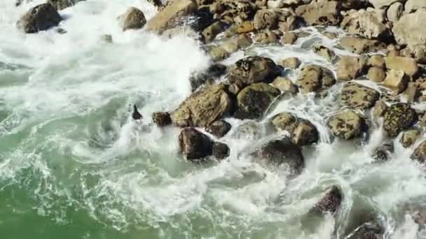 Верхний вид океанических волн, падающих на камни и скалы с брызгами и белой пеной. Каменное побережье. — стоковое видео