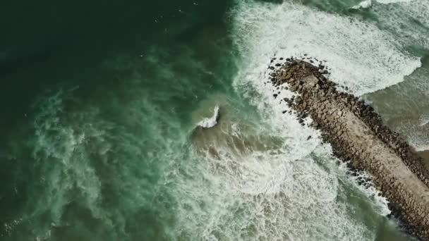 Aerial view of Atlantic ocean waves crushing on rocky pier or breakwater. Costa Da Caparica, Setubal, Almada, Portugal Видеоклип