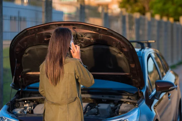 Νεαρή γυναίκα στέκεται κοντά σε σπασμένο αυτοκίνητο και ζητά βοήθεια ή βοήθεια — Φωτογραφία Αρχείου