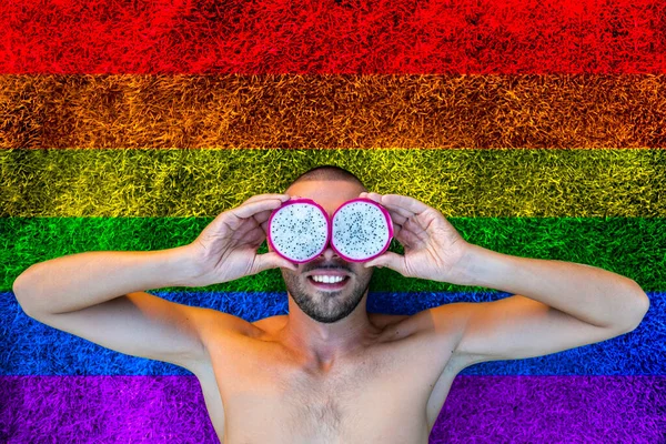 Homossexual bonito homem com fruta de dragão em vez de seus olhos no fundo símbolo lgbt arco-íris. Apoio aos direitos das comunidades lésbicas, gays, bissexuais e transexuais. Mostre suas verdadeiras cores — Fotografia de Stock