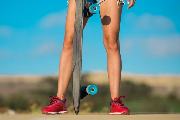 Sportig kvinna som håller skateboard eller longboard på en solig sommardag. — Stockfoto