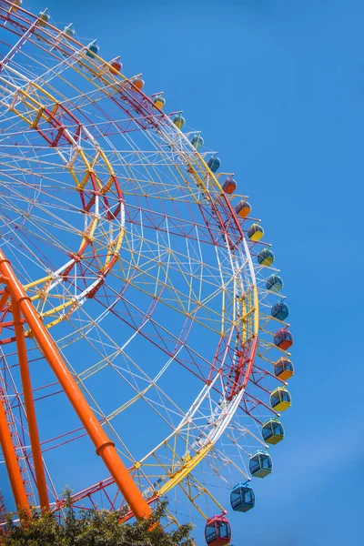 Une grande roue ferris colorée isolée sur fond de ciel bleu dans un parc d'attractions. — Photo