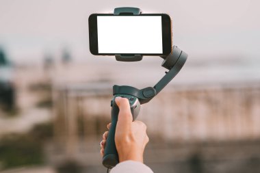 Boş ekranlı akıllı telefon için bir kadın eli. Vlog ve video günlük tutma kavramı.