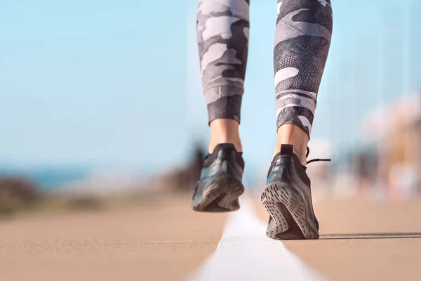 Futó lábak futnak az út közelségében a cipőn. A nő a szabadban edz. Egészséges életmód, edzés, wellness koncepció — Stock Fotó