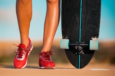 Güneşli bir yaz gününde kaykaylı ya da uzun kaykaylı bir kadın. Ayakkabıları kapat.