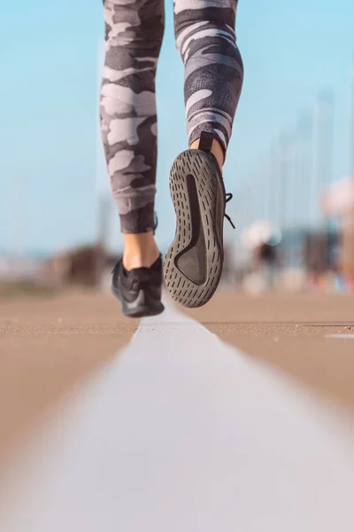 Donna atleta in forma che corre sulla strada. Runner scarpe da vicino — Foto Stock