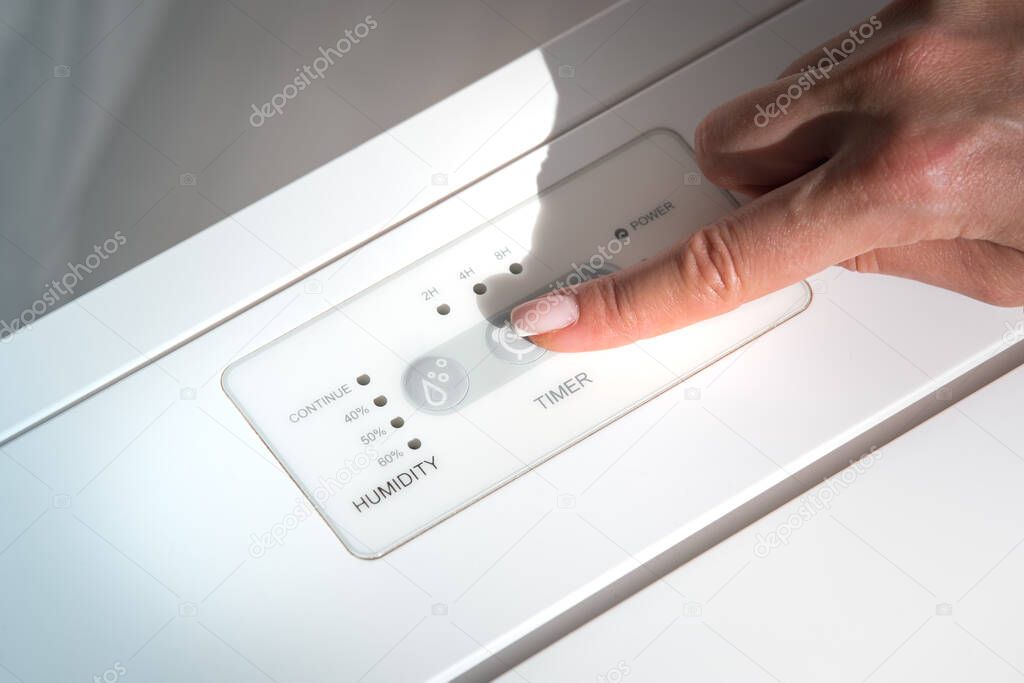 Woman turning on air dryer, purifier, dehumidifier, humidity indicator, air ionizer or water container.