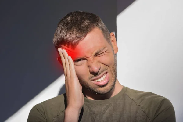 Unge man vidrör sitt tempel och har stark spänningshuvudvärk. Klusterhuvudvärk. Man som lider av migrän, stress, baksmälla med röd accent. Händerna på huvudet — Stockfoto