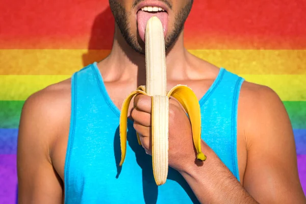 Ung homosexuell man sexig slickar en halv-skalad gul banan på en gay stolthet fest. Lesbisk, homosexuell, bisexuell, stöd för transsexuella rättigheter. HBTQ regnbåge symbol — Stockfoto