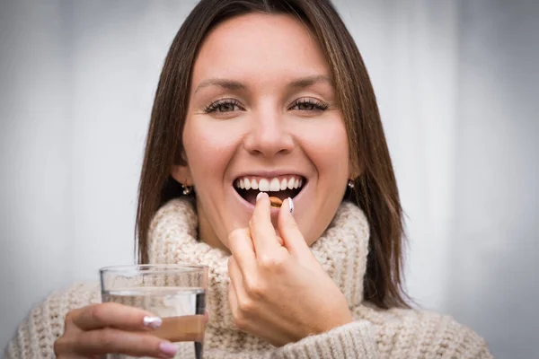 Wanita cantik yang tersenyum muda meminum pil minyak ikan. Mengambil kapsul dengan omega 3 atau vitamin D3. Suplemen Vitamin D — Stok Foto