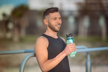 Genç fitness adamı egzersiz sırasında tekrar kullanılabilir şişeden limonla su içiyor. Egzersiz yaparken içmek. Antrenman sırasında susuzluk