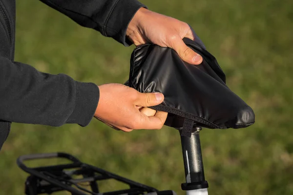 Hombre poniendo cubierta de lluvia negra en la silla de montar de la bicicleta. Cubierta de asiento impermeable para bicicletas. Cuidado del asiento de bicicleta — Foto de Stock