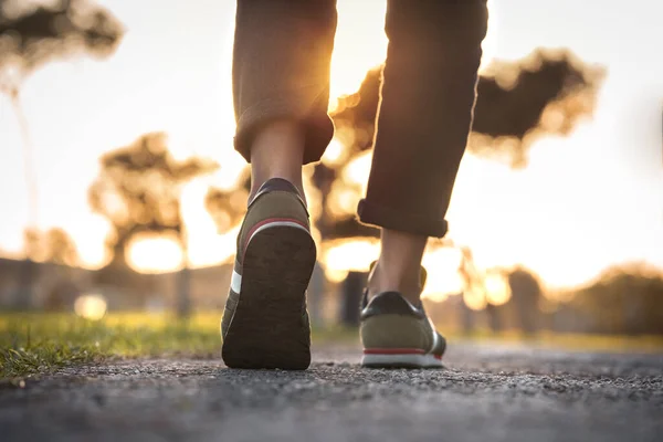 Frau geht bei Sonnenuntergang im Freien spazieren. Nahaufnahme auf Schuhen mit hochgekrempelten Jeans. Einen Schritt machen. Neues Lebenskonzept — Stockfoto