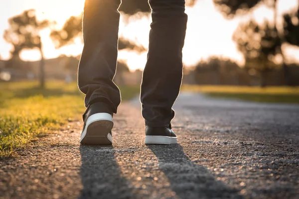 Mann, der bei Sonnenuntergang im Park spazieren geht. Nahaufnahme auf Schuh, einen Schritt machen. — Stockfoto