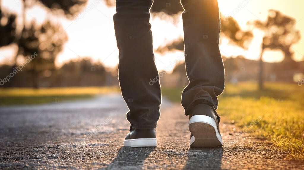 Man walking outdoors in the park at sunset. Closeup on shoe. Concept of new start and freedom