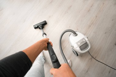 Evde elektrikli süpürge kullanan bir adam. Adam evi temizliyor. Ev idaresi konsepti. Birinci şahıs görünümü