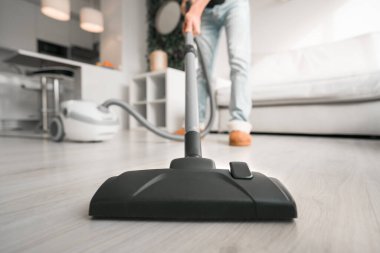 Evde elektrikli süpürge kullanan bir adam. Adam evi temizliyor. Ev idaresi konsepti. Elektrik süpürgesini kapat.
