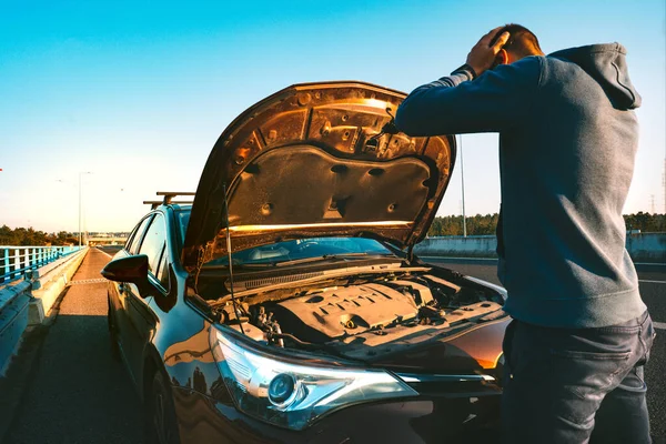 Stressad man som har problem med sin trasiga bil på landsvägen. Mannen som tittar under motorhuven. Bilen går sönder på autobahn. Begreppet vägassistans. — Stockfoto