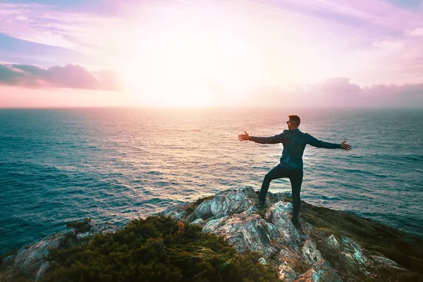 Вид сзади на человека с открытыми руками, наслаждающегося свободой и закатом или восходом солнца на вершине горной скалы с видом на океан. Наслаждаясь природой и жизнью. Путешествие в Португалию, Cabo Espichel. — стоковое фото