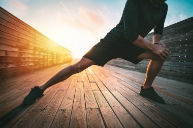 Spor salonundaki adam antrenmandan önce bacaklarını açıyor. Koşmadan önce ısınıyorum. Spor ve sağlıklı yaşam tarzı.