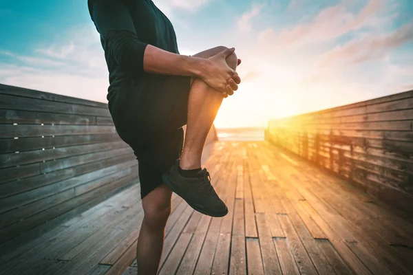 Fitness férfi bemelegítő és nyújtózkodó lábak edzés előtt szabadban naplementekor vagy napkeltekor. Sport és egészséges életmód — Stock Fotó