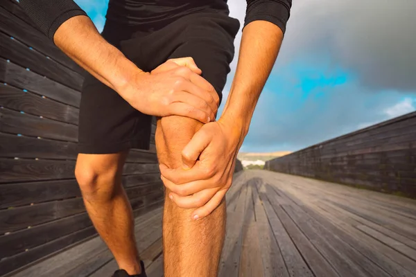 Homem corredor segurando seu joelho doloroso por causa de lesão. Lesão por exercício e exercício — Fotografia de Stock