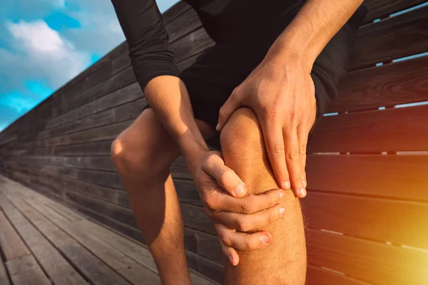 Homem segurando o joelho doloroso. Lesão e dor no joelho do atleta. Lesão por exercício — Fotografia de Stock